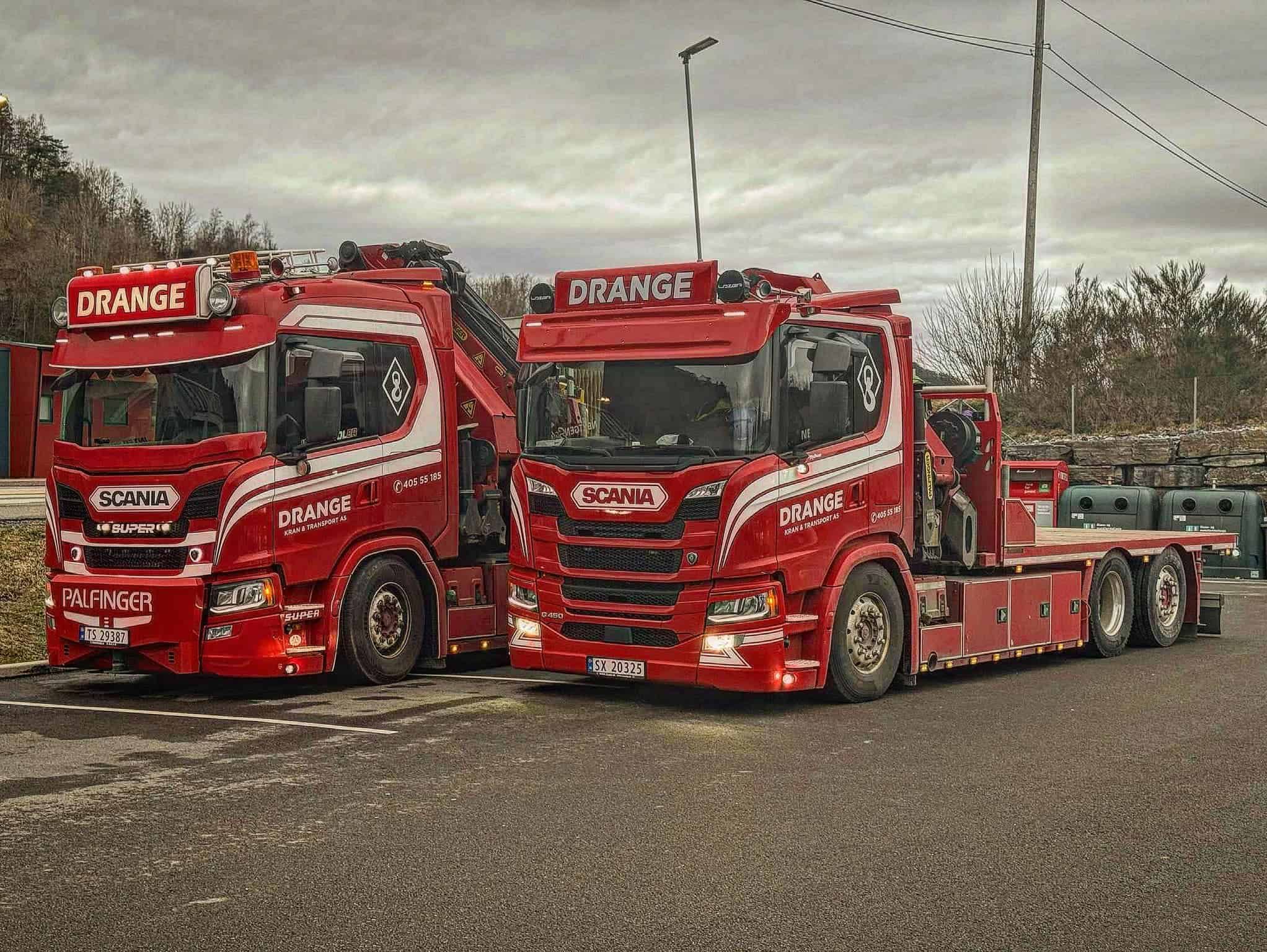 To røde Drange lastebiler parkert side om side.